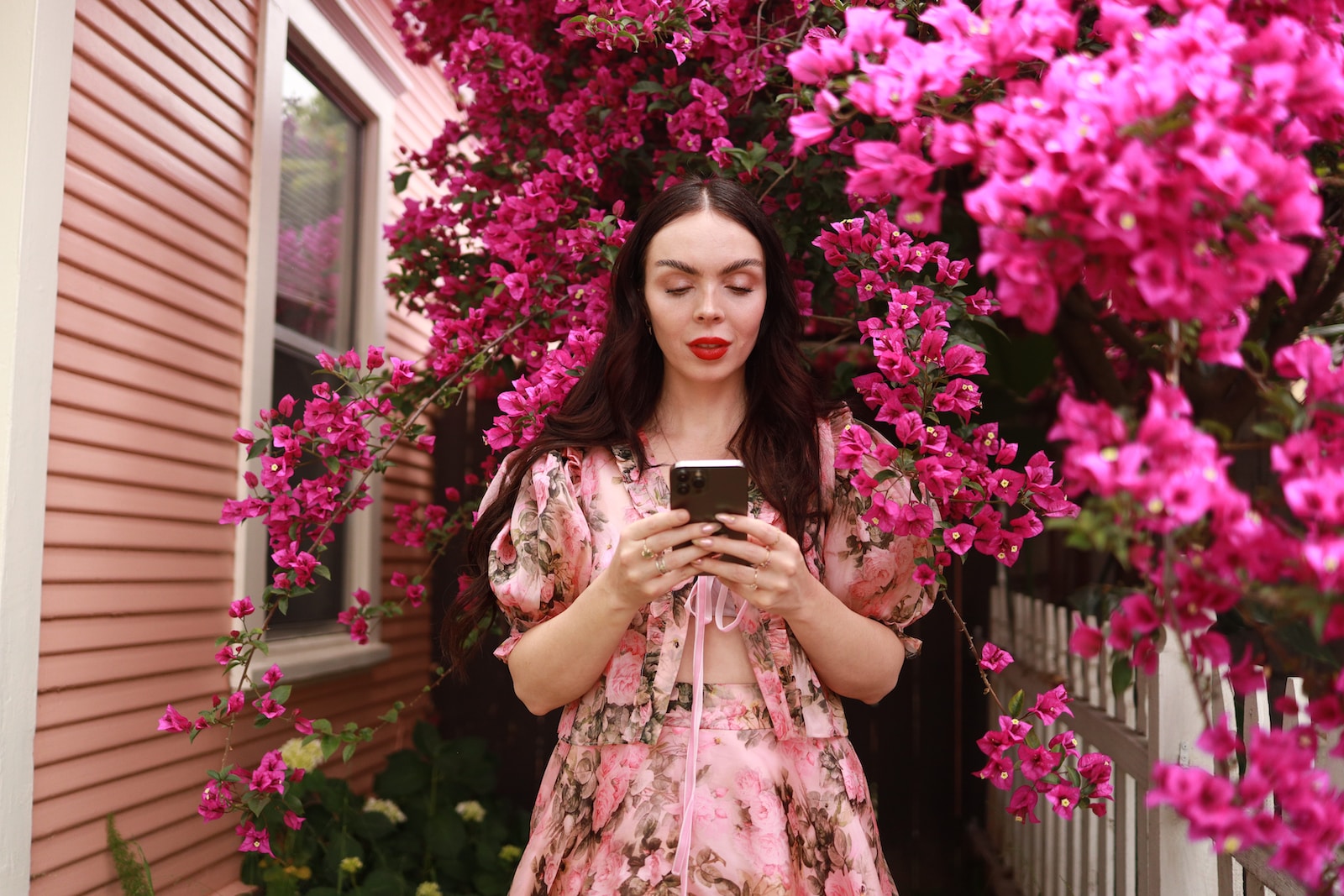 a woman in a pink dress looking at a cell phone